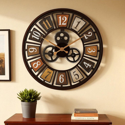 Decorative wall clock with gear design on a beige wall, below a framed picture and books on a wooden shelf.