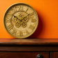 Decorative clock with gear design on an orange wall